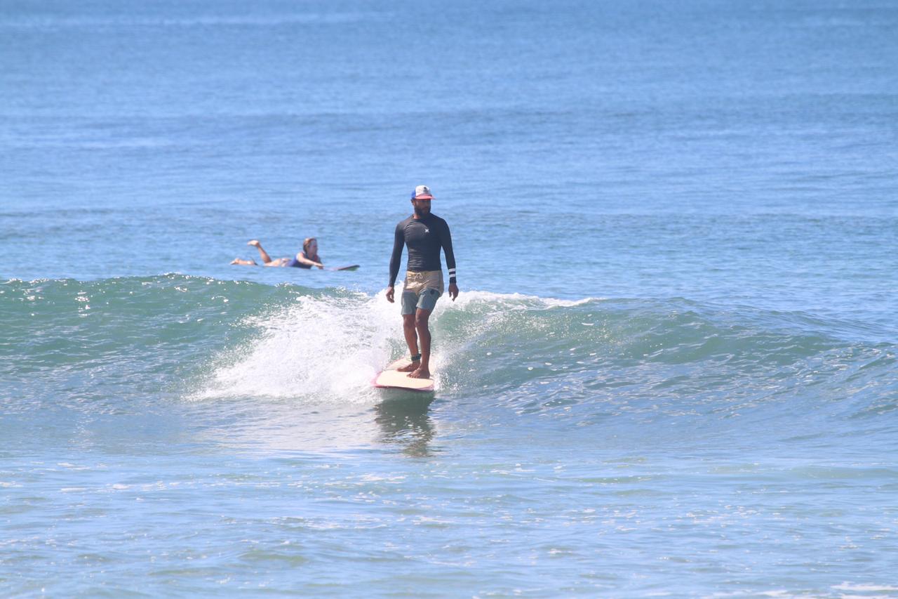 Eli cross-stepping on a longboard along a clean Costa Rica wave