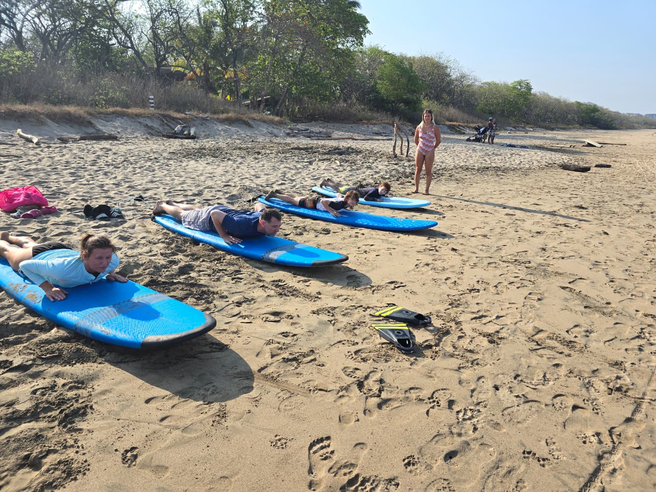Students lying on boards practicing paddling on the beach