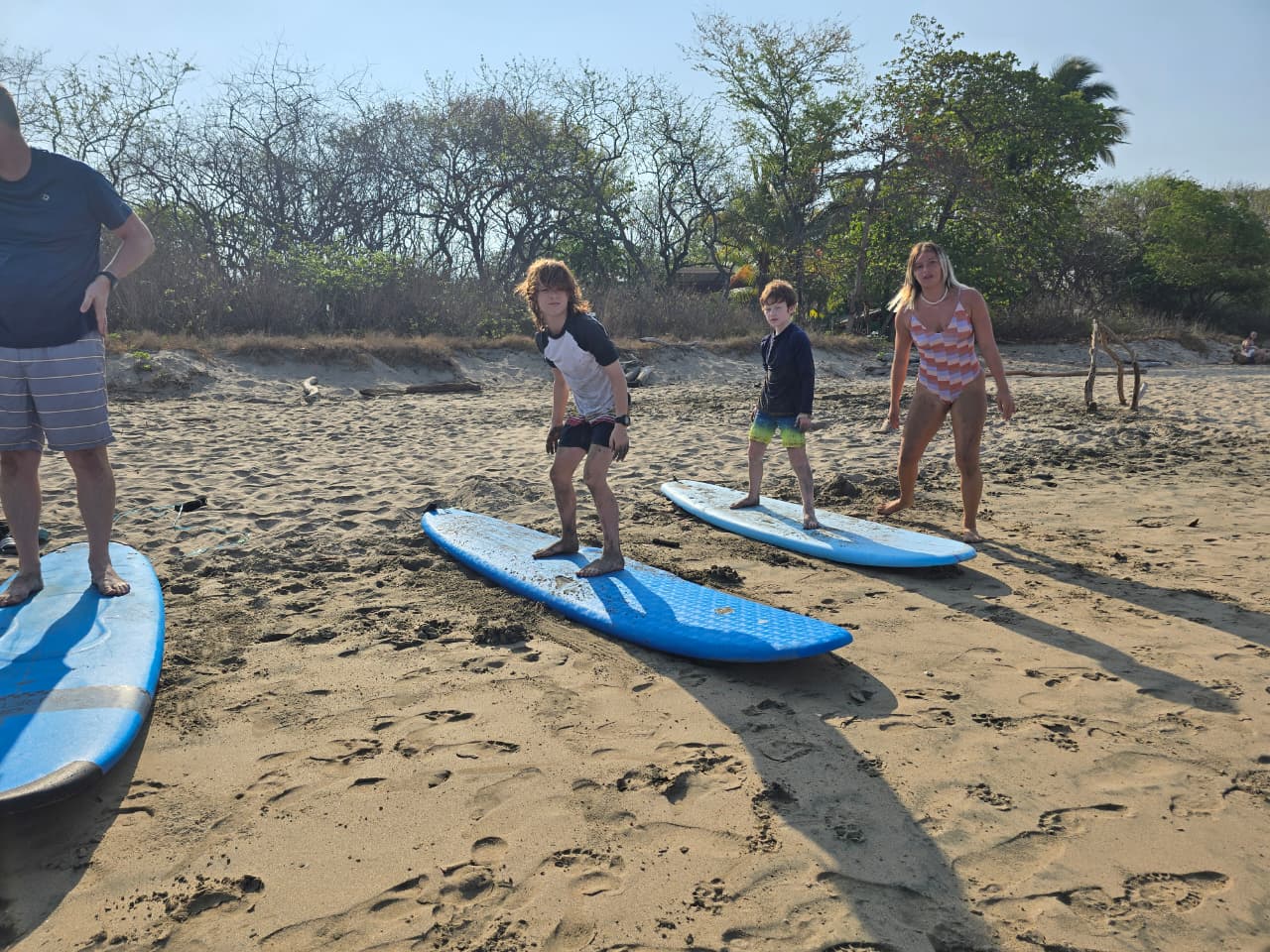 Students practicing pop-ups on soft-top boards on the sand